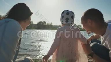 幸福的年轻家庭和一个小女儿在沙滩上一起享受日落在城市<strong>湖岸</strong>。 夏季